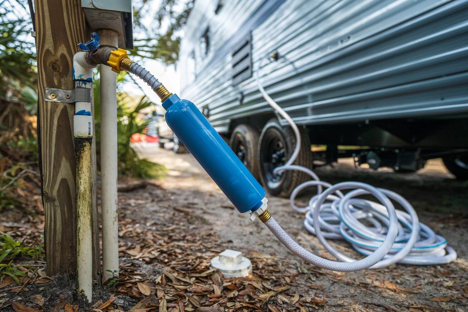 Boyau d’eau raccordé à une roulotte pour l’alimentation en eau potable sur un terrain de camping.